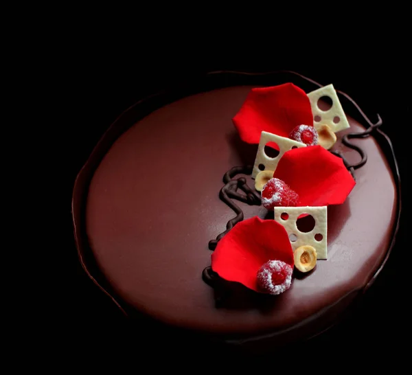 Torta romántica de chocolate con pétalos de rosa, decoraciones de chocolate blanco y bayas frescas sobre fondo negro — Foto de Stock