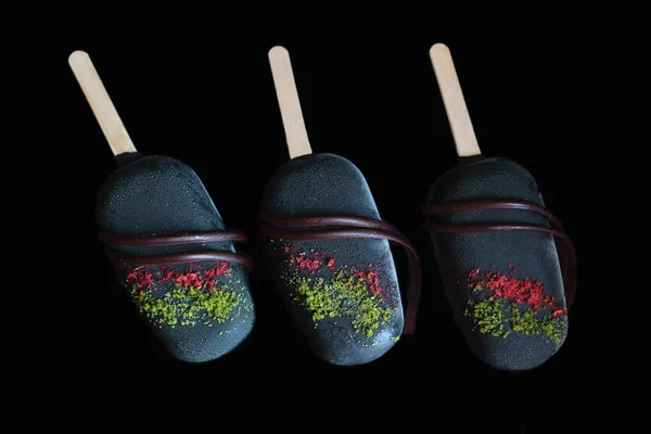 Gelado colorido escuro gelado picolés vidrados com chocolate escuro isolado em fundo preto — Fotografia de Stock