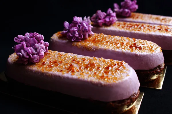 Flores de primavera Creme Brulee postres no horneados con flores de color lila fresco y cobertura de caramelo aislado sobre fondo negro — Foto de Stock