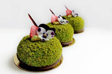 Yenilebilir pansy çiçek ve kurutulmuş çilek ile üç yeşil dokulu antep fıstığı tatlılar