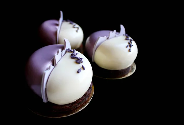 Desserts ronds en mousse lavande violette et blanche avec pétales de lavande sur fond noir — Photo