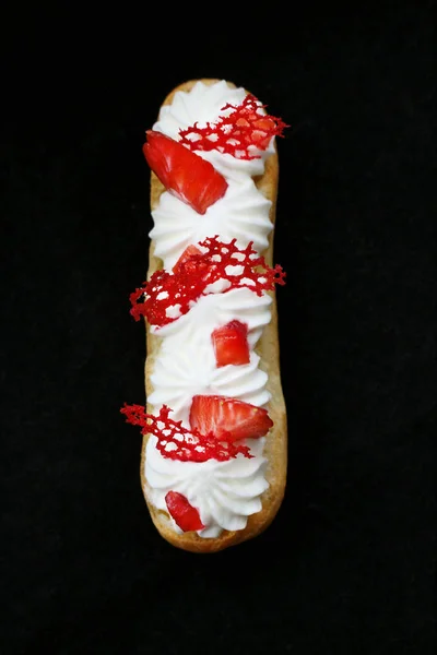 Aardbeien en crème Eclair met verse bessen en rode kant tuile top down op zwarte achtergrond — Stockfoto