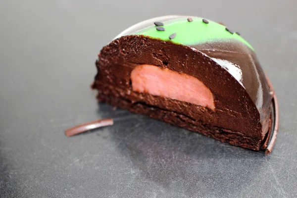 Dessert en mousse d'avocat et chocolat avec glaçure miroir et graines de sésame noir découpées sur table en acier rayé — Photo