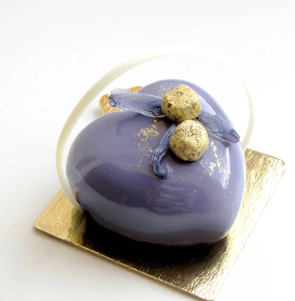 Postre en forma de corazón púrpura con decoraciones de oro y anillo de chocolate blanco en posavasos dorados — Foto de Stock