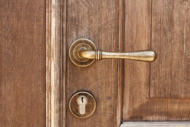 Bronz kapı kolu ve modern anahtar deliği ile kahverengi ahşap giriş kapısı