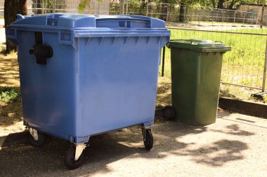 Güneşli bir günde açık havada renkli mavi ve yeşil çöp konteynerleri