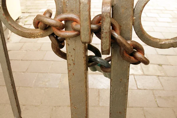 Porte métallique fermée avec chaîne et cadenas sur allée pavée grise — Photo