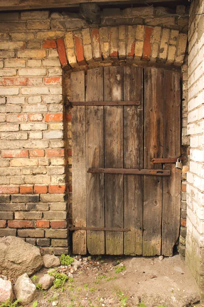 Érlelt sötét fából készült ajtó a viharban piszkos fal — Stock Fotó
