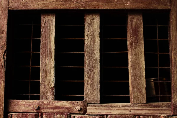 Eski kahverengi ahşap duvarda ürpertici koyu hücre penceresi — Stok fotoğraf