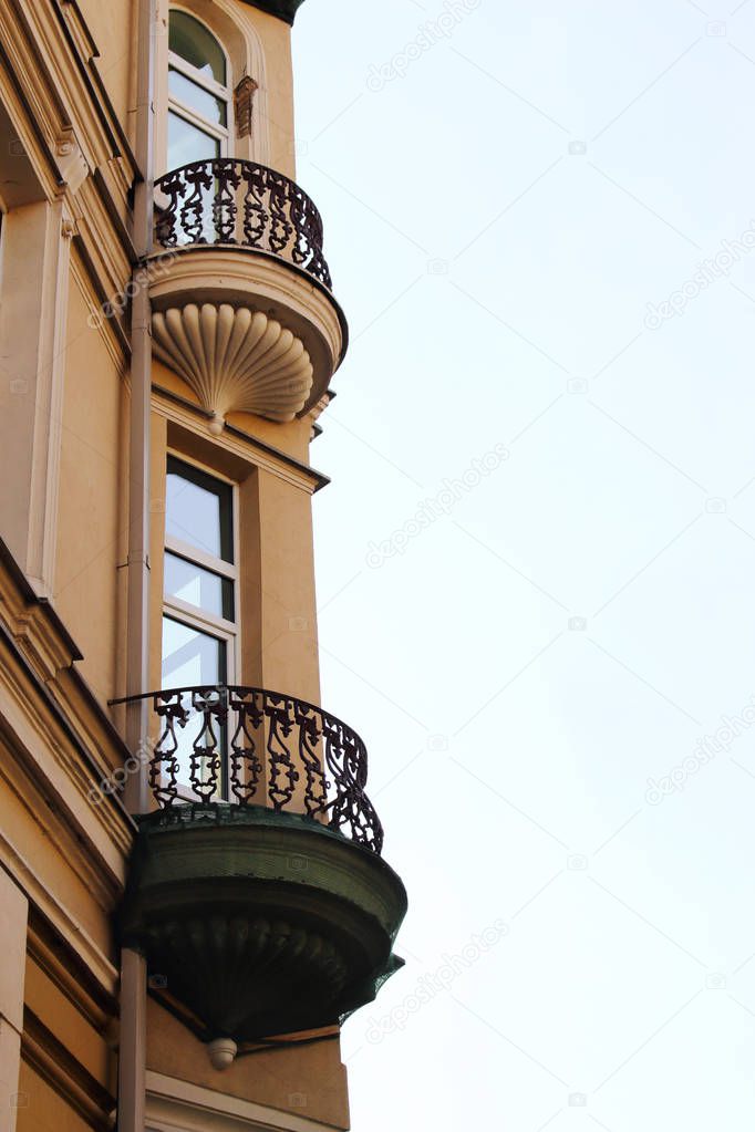 Old town architecture building corner with rounded balconies on light sky background