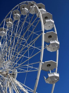 Mavi gökyüzü arka planında dönen boş beyaz dönme dolap