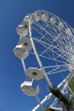 Mavi gökyüzü arka planında dönen boş beyaz dönme dolap