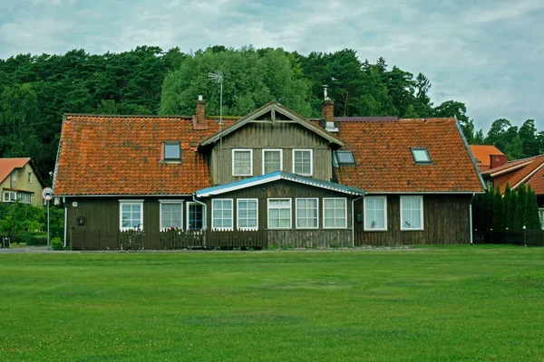 Vecchio villaggio casa in legno cortile anteriore con tetto rosso e foresta dietro — Foto Stock