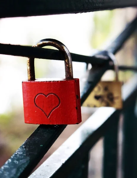 Red square metal wedding lock with a heart hanging on a handrail — Stock Photo, Image