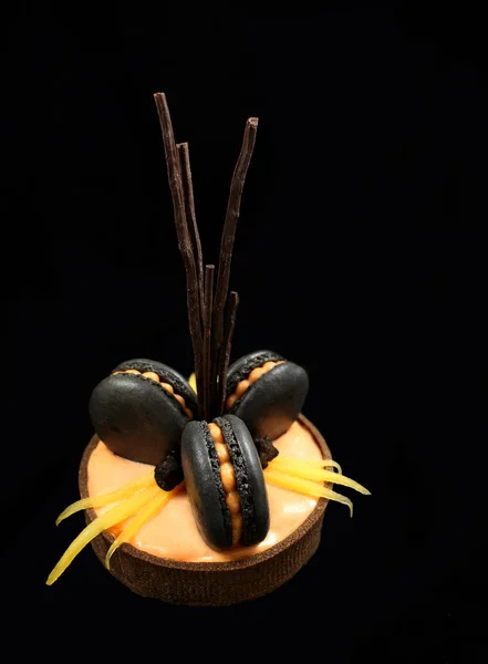 Orange chocolate tart with black macarons and persimmon on black