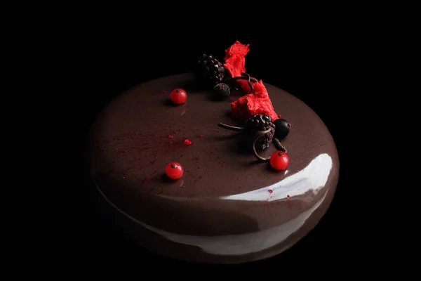 Torta redonda de chocolate con bayas y esponja roja sobre fondo negro — Foto de Stock