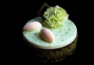 Açık yeşil şam fıstıklı, yuvarlak çikolatalı kek ve taze yeşil karanfil çiçeği.