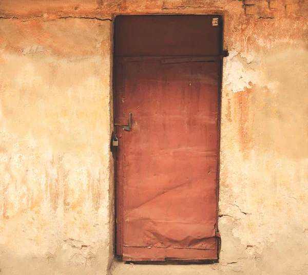 Red metal door on light exterior wall with a lock