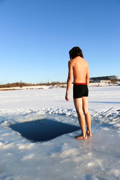 赤ひげと長髪 黒のショート パンツで 裸で若い スリム ハンサムなスポーティな男 ウクライナに産業景観の背景に 冬の冷たい水に飛び込む — ストック写真