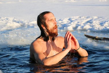 Genç bir adam buz çukuruna dalmaya hazırlanıyor. Kış, soğuk, açık deniz.