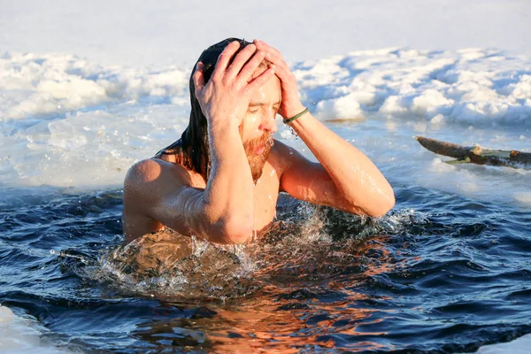 Un giovane uomo si sta preparando a tuffarsi nella buca di ghiaccio. Inverno, freddo, acqua aperta . — Foto Stock