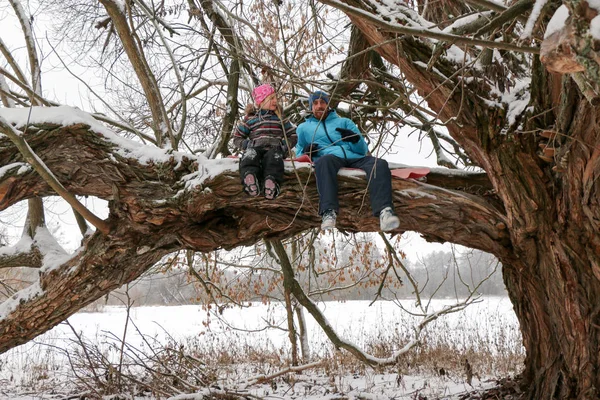 Junge Liegeplatz Mann mit kleinem Mädchen haben Spaß im verschneiten Wald im Winter. — Stockfoto