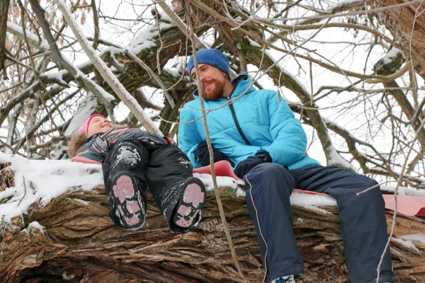 Mladí berded muž s malou holkou bavit v zasněženém lese v zimě. — Stock fotografie