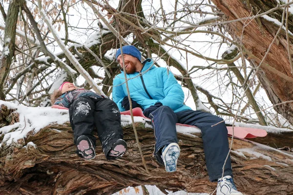 Junge Liegeplatz Mann mit kleinem Mädchen haben Spaß im verschneiten Wald im Winter. — Stockfoto