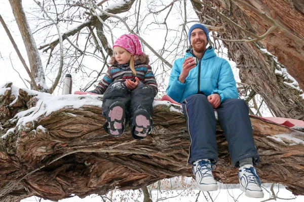 Junge Liegeplatz Mann mit kleinem Mädchen haben Spaß im verschneiten Wald im Winter. — Stockfoto