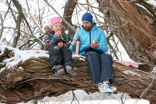 Junge Liegeplatz Mann mit kleinem Mädchen haben Spaß im verschneiten Wald im Winter. — Stockfoto