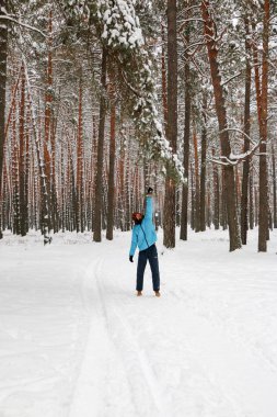 Kış çam ormanı içinde kırmızı sakallı neşeli yakışıklı bir genç adam portresi. Bir kış günü kar çam şubesinden patlatmış. Uzun boylu bir çamları. dikey odaklı