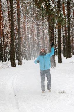 Kış çam ormanı içinde kırmızı sakallı neşeli yakışıklı bir genç adam portresi. Bir kış günü kar çam şubesinden patlatmış. Uzun boylu bir çamları. dikey odaklı