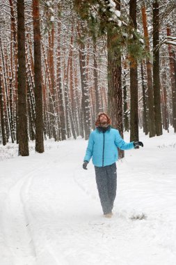 Kış çam ormanı içinde kırmızı sakallı neşeli yakışıklı bir genç adam portresi. Bir kış günü kar çam şubesinden patlatmış. Uzun boylu bir çamları. dikey odaklı