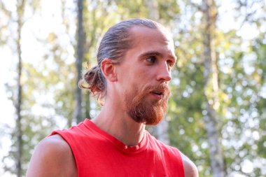 Kızıl Sakal ve uzun saç ormandaki neşeli yakışıklı bir genç adam portresi. Güneşli yaz gün