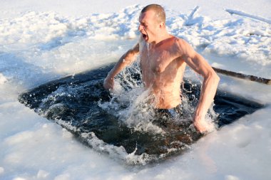 Parlak güneşli bir günde, bir karlı manzara karşı Kışın buzlu suya dalış bir genç, ince, yakışıklı, atletik ve güçlü adam, çıplak, güzel birçok damla ve su sıçramalarına. Ukrayna, Shostka
