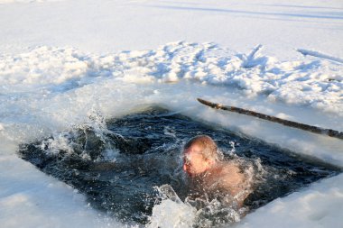 Parlak güneşli bir günde, bir karlı manzara karşı Kışın buzlu suya dalış bir genç, ince, yakışıklı, atletik ve güçlü adam, çıplak, güzel birçok damla ve su sıçramalarına. Ukrayna, Shostka
