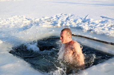 Parlak güneşli bir günde, bir karlı manzara karşı Kışın buzlu suya dalış bir genç, ince, yakışıklı, atletik ve güçlü adam, çıplak, güzel birçok damla ve su sıçramalarına. Ukrayna, Shostka