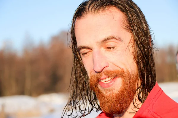 Young Good Looking And Attractive Man With Muscular Body, with a red beard and long hair Wet Taking after taking an ice bath. handsome attractive men showering next to swimming pool. water drops are falling on his torso. Sunny winter day in Ukraine,
