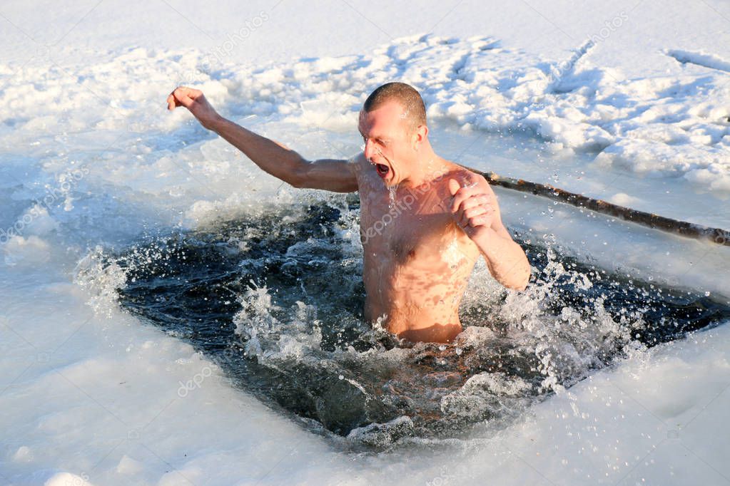 A young, slim, handsome, strong, athletic man, naked, diving into the icy water in the winter, against a snowy landscape, a bright sunny day, many beautiful drops and splashes. Ukraine, Shostka