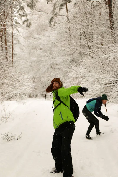 Beautiful happy couple throwing snowballs and having fun in winter park. People walk in the woods in winter. Lots of snow, fabulous nature. Boy and girl Young couple Lovers walk in nature. Friends enjoy the beautiful pine forest.