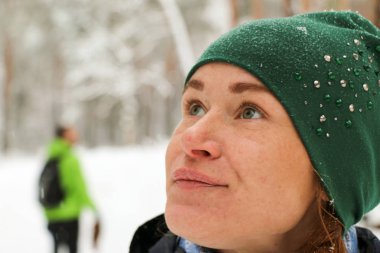 İnsanlar kışın ormanda yürürler. Bir sürü kar, muhteşem doğa. Erkek ve kız. Genç çift, doğada yürür. Dostlar güzel çam ormanının tadını çıkarın. Büyük portreler, mutlu yüz, gülümseme, düşen kar taneleri.