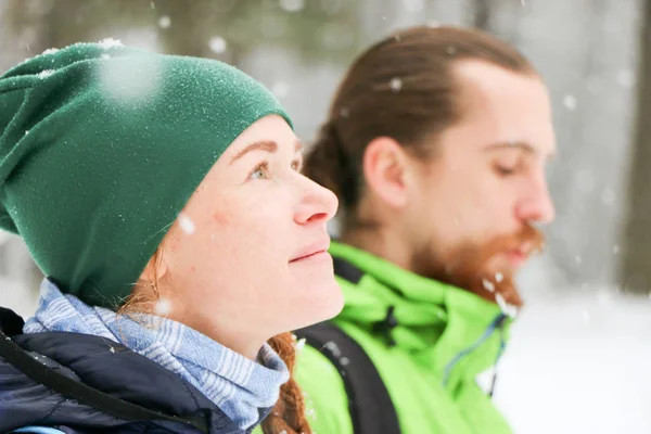 People walk in the woods in winter. Lots of snow, fabulous nature. Boy and girl Young couple Lovers walk in nature. Friends enjoy the beautiful pine forest. large portraits, happy face, smile, falling snowflakes