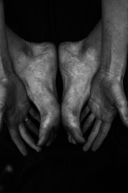 Kadın bacakları, eller. Güzel ayaklar ve avuçlar siyah arka planda, yakın plan. Siyah beyaz fotoğraf, doğal ışık..