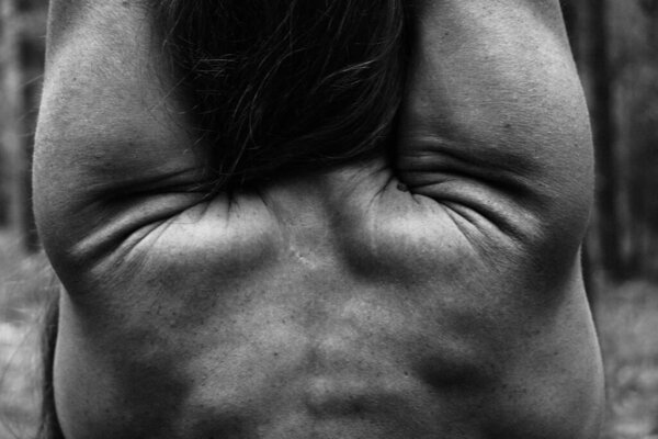 Close-up graceful pose of female naked back. Beautiful athletic female body, prominent muscles. Black and white photo, natural light.