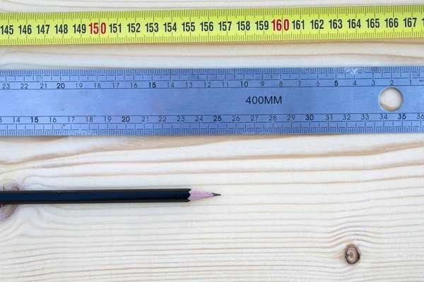 Pencil, rule and a meter on a wooden background