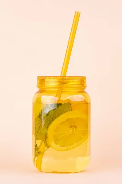 Orange mason jar of lemonade with lemons ,mint, ice and straw on