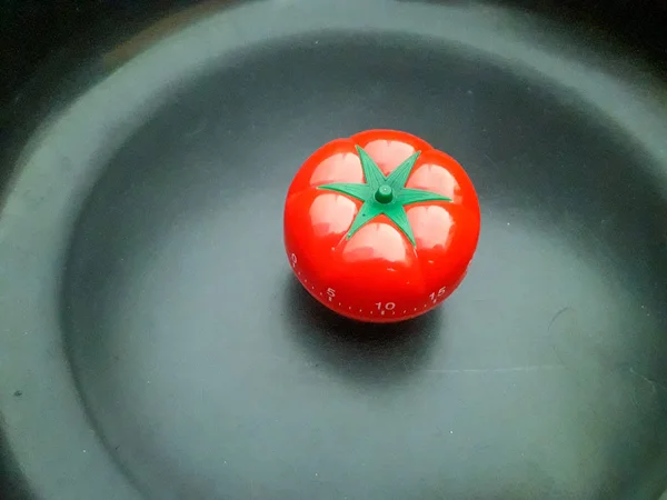 Temporizador pomodoro rojo en forma de tomate sobre fondo de textura negra . — Foto de Stock