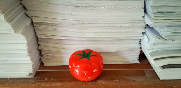 Pomodoro timer in background of paper textures piled. Stock Image