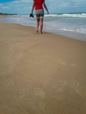 Kumda ayak izleri bırakarak kum plajı üzerinde yürüyen kadın. Brezilya kadın ayak detay.