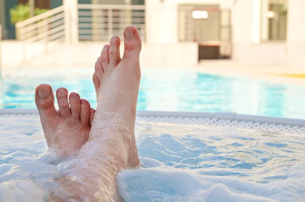 Relax in jacuzzi at a holiday resort, male feet - point of view perspective